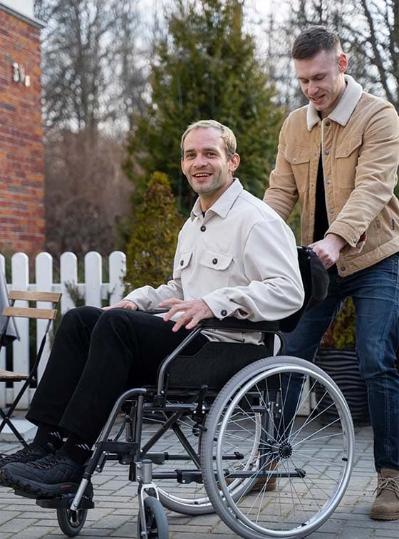 Assistant helping person in wheelchair outdoors